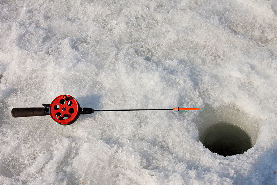 ice fishing scene sowing a jig rod next to a hole drilled into the lake