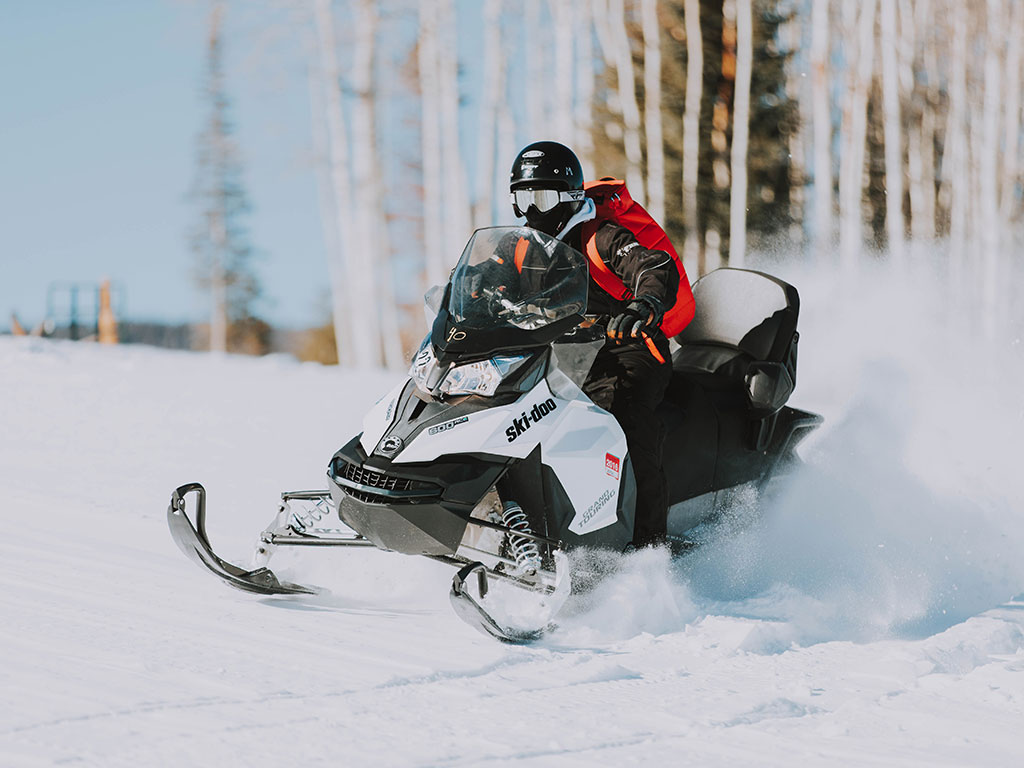 winter snow scene with person riding a snowmobile